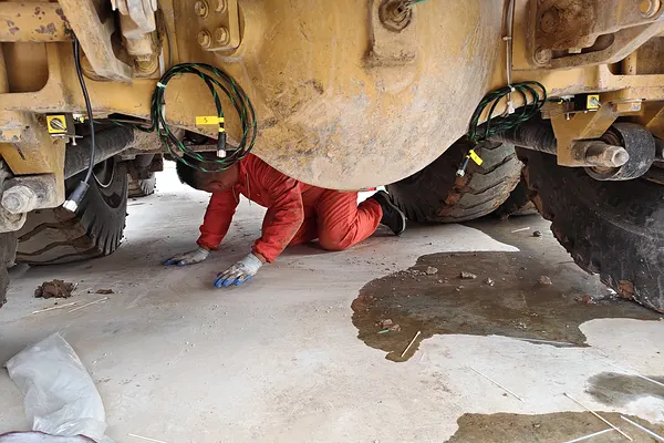 Technician fitting a GX-6 sensor under a wheel loader